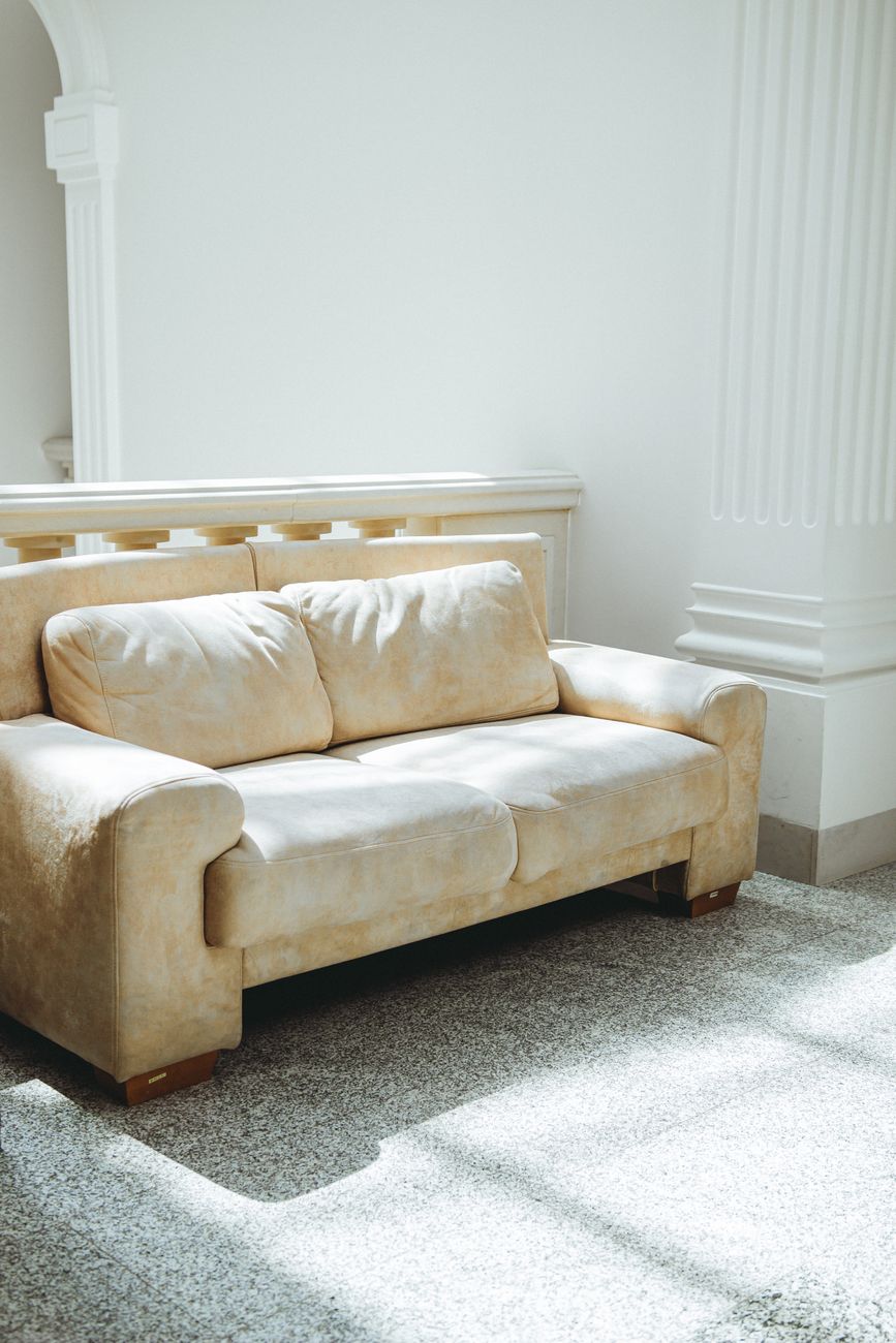 A neutral linen sectional sofa in a sunlit living room, styled simply with one throw and no extra decoration.
