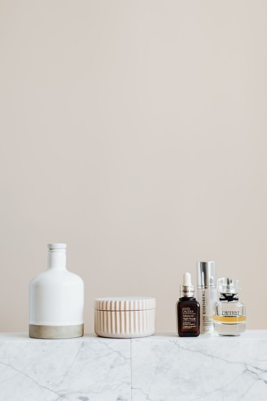 A minimal bathroom shelf with three moisturizer jars of different sizes, no other clutter in frame.