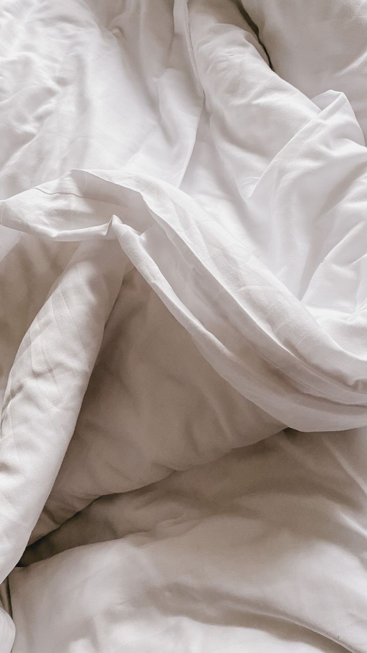 Neatly folded white percale sheets showing the soft matte finish and dense weave of a properly finished heritage cotton.