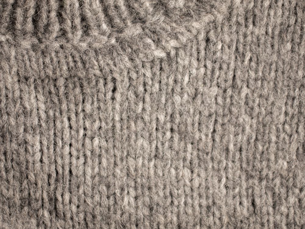 Close view of a light beige knit collar showing the soft, uneven texture of fine wool yarn.